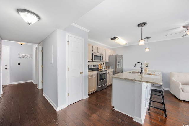 kitchen featuring sink, a breakfast bar, appliances with stainless steel finishes, light stone counters, and decorative light fixtures