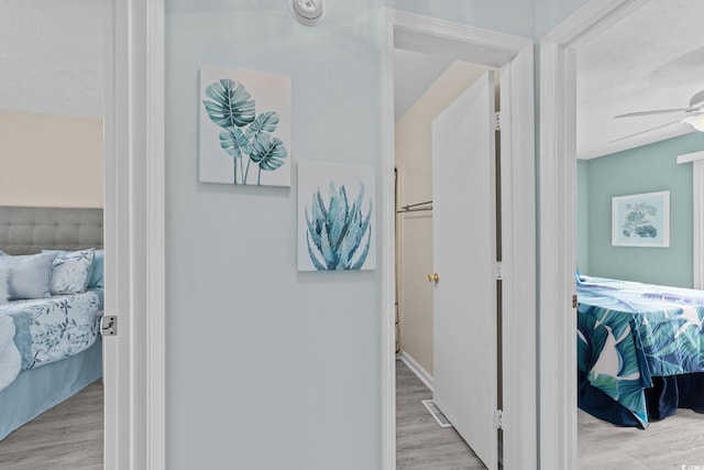 hallway with a textured ceiling and light hardwood / wood-style floors