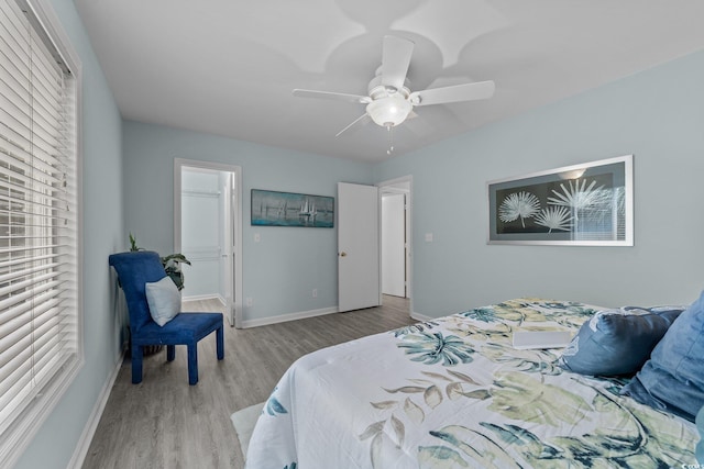 bedroom featuring ceiling fan, a closet, light hardwood / wood-style floors, and multiple windows