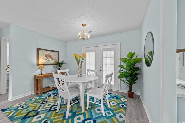 dining space featuring french doors, hardwood / wood-style flooring, an inviting chandelier, and a textured ceiling