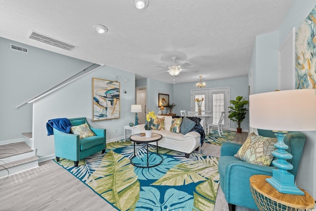 living room featuring a textured ceiling, light hardwood / wood-style floors, and ceiling fan