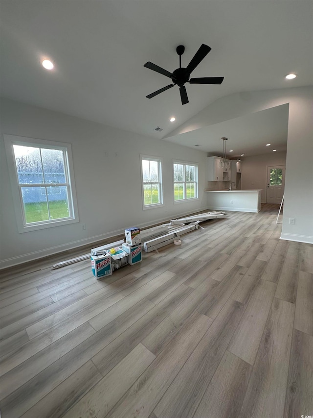 interior space with light wood-type flooring, lofted ceiling, and ceiling fan