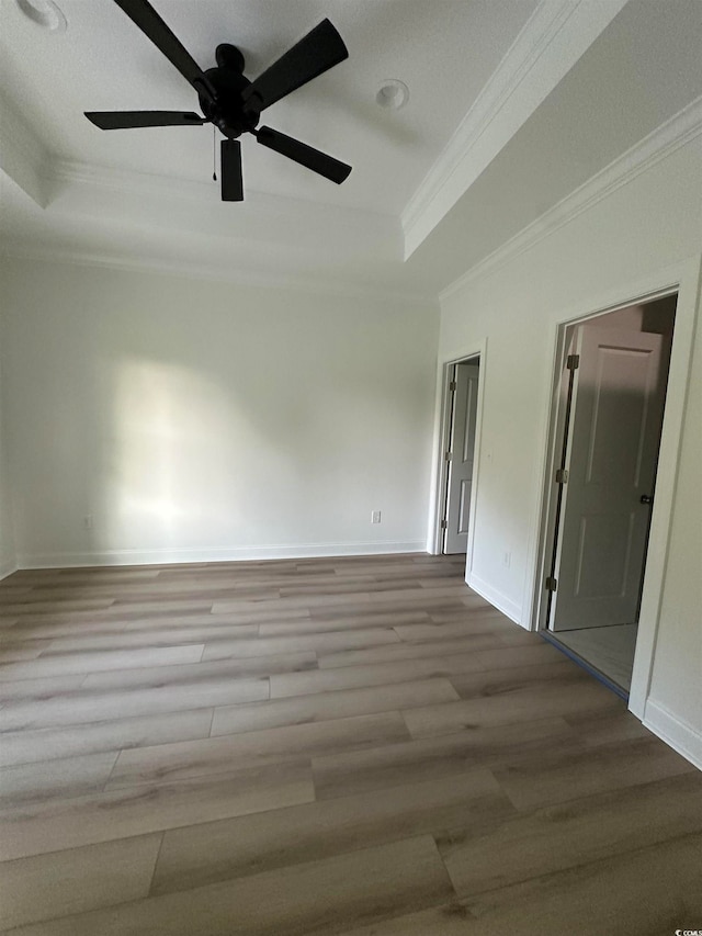 spare room with light wood-type flooring, ceiling fan, crown molding, and a tray ceiling