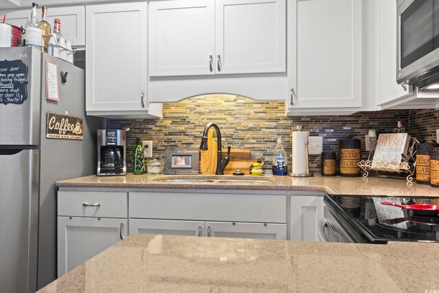 kitchen with white cabinets, backsplash, and stainless steel appliances