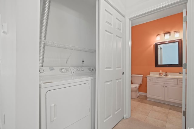 clothes washing area with separate washer and dryer, sink, and light tile patterned floors