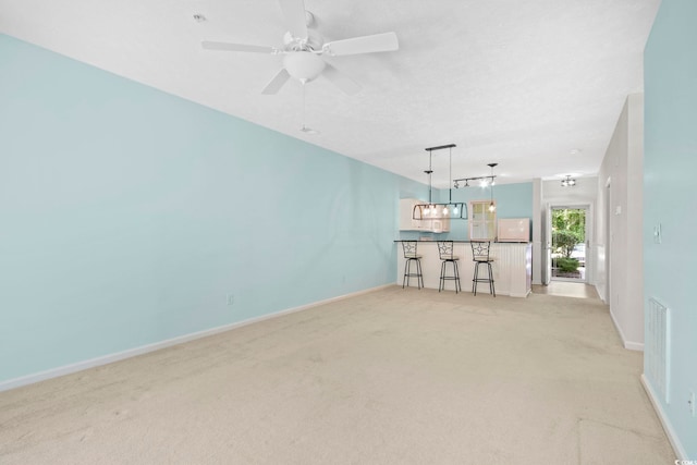 unfurnished living room featuring ceiling fan, indoor bar, and light colored carpet