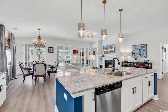 kitchen with pendant lighting, sink, a kitchen island with sink, stainless steel dishwasher, and french doors