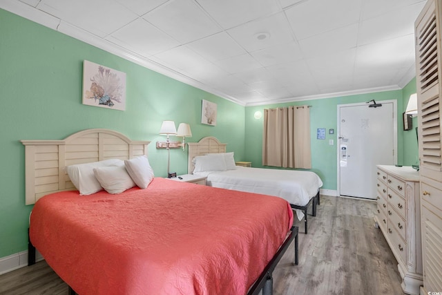 bedroom featuring wood finished floors, baseboards, and ornamental molding