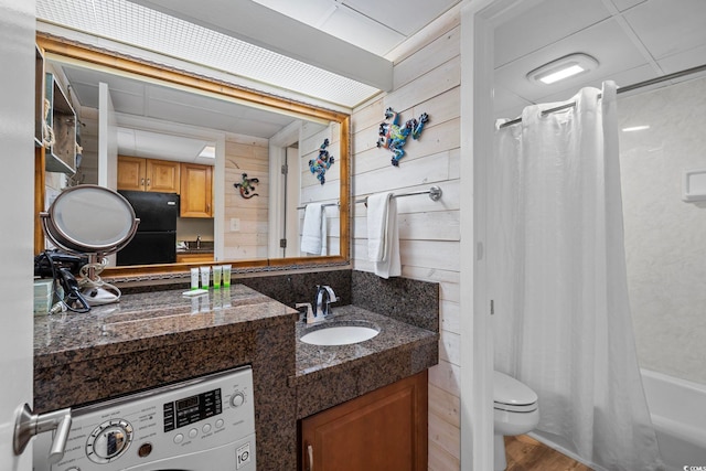 full bathroom with wooden walls, washer / clothes dryer, toilet, and vanity