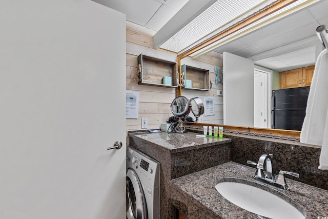 bathroom with tasteful backsplash, wooden walls, washer / dryer, and vanity