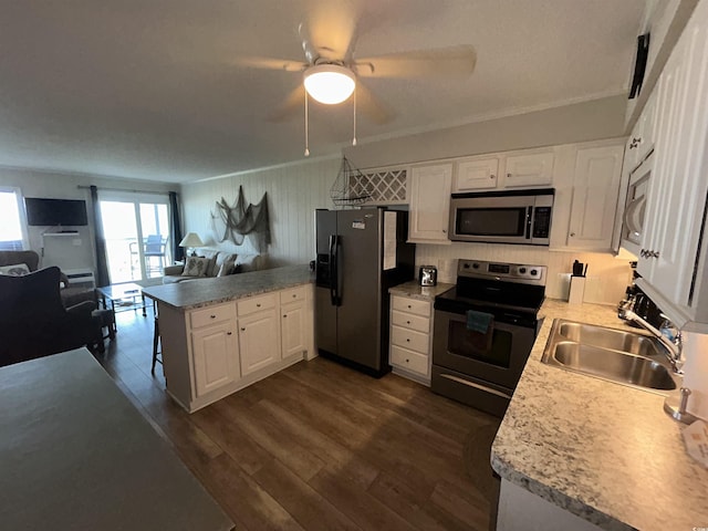 kitchen featuring sink, appliances with stainless steel finishes, white cabinetry, dark hardwood / wood-style floors, and kitchen peninsula