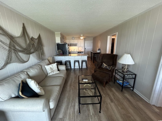 living room featuring hardwood / wood-style flooring, a textured ceiling, and ceiling fan