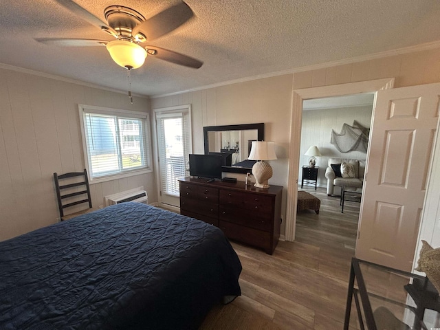 bedroom featuring ornamental molding, wood-type flooring, and a textured ceiling