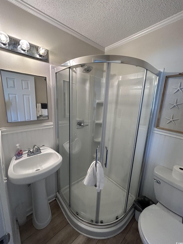 bathroom featuring crown molding, toilet, an enclosed shower, and a textured ceiling