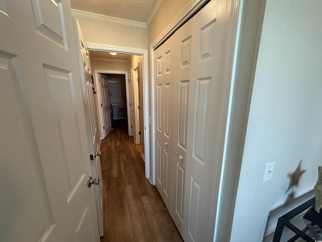 corridor featuring dark wood-type flooring, ornamental molding, and a textured ceiling