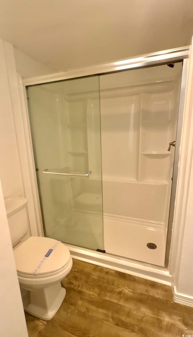 bathroom with walk in shower, wood-type flooring, and toilet