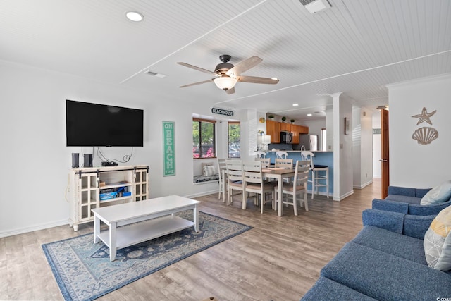 living room featuring ceiling fan, decorative columns, and light wood-type flooring