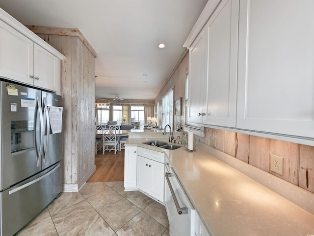 kitchen featuring dishwasher, sink, ceiling fan, stainless steel fridge with ice dispenser, and white cabinets