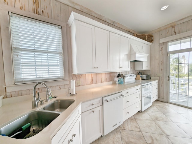 kitchen with white cabinetry, premium range hood, white appliances, and sink