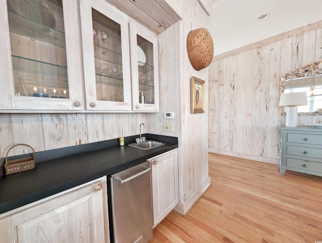 kitchen featuring white cabinets, dishwasher, wooden walls, light hardwood / wood-style flooring, and sink