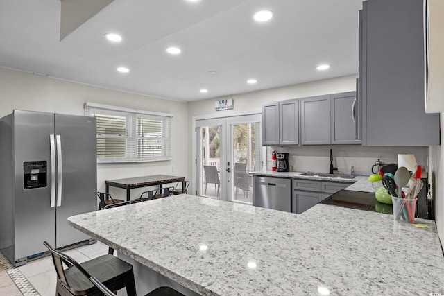 kitchen featuring french doors, light stone countertops, stainless steel appliances, sink, and kitchen peninsula