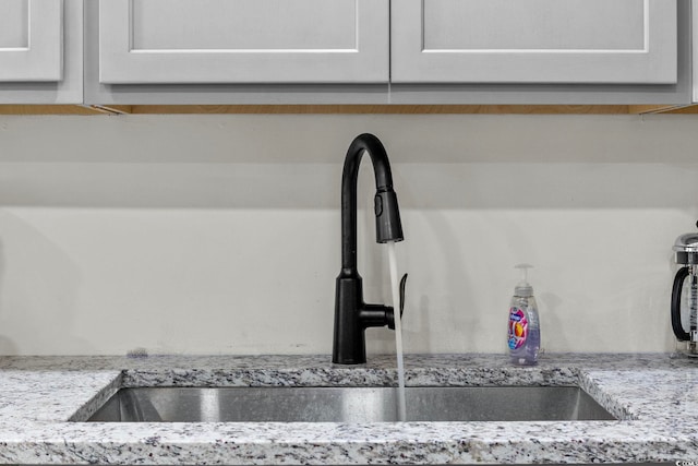 room details with light stone countertops, white cabinetry, and sink