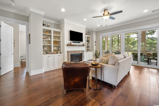 living room with dark wood-type flooring, crown molding, a fireplace, and ceiling fan