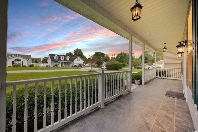 patio terrace at dusk with a porch and a lawn