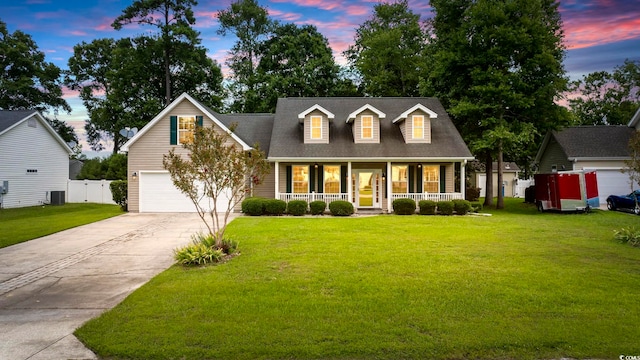 cape cod house featuring a yard, a garage, covered porch, and central AC