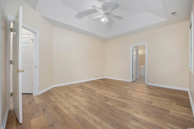 unfurnished room featuring light hardwood / wood-style flooring, ceiling fan, and a raised ceiling