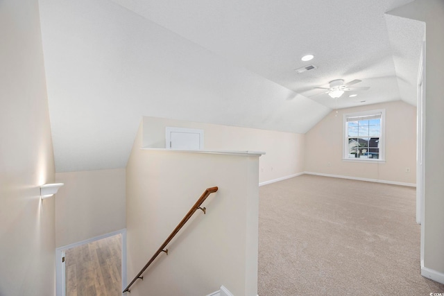 additional living space with a textured ceiling, ceiling fan, light carpet, and vaulted ceiling