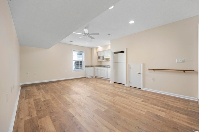 unfurnished living room featuring a textured ceiling, ceiling fan, and light hardwood / wood-style floors