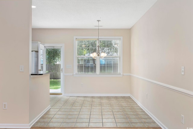 unfurnished dining area with a textured ceiling, plenty of natural light, an inviting chandelier, and light tile patterned floors