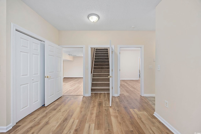 interior space with a textured ceiling, light hardwood / wood-style flooring, and a closet