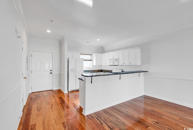 kitchen featuring kitchen peninsula, white appliances, white cabinetry, a breakfast bar area, and light hardwood / wood-style floors