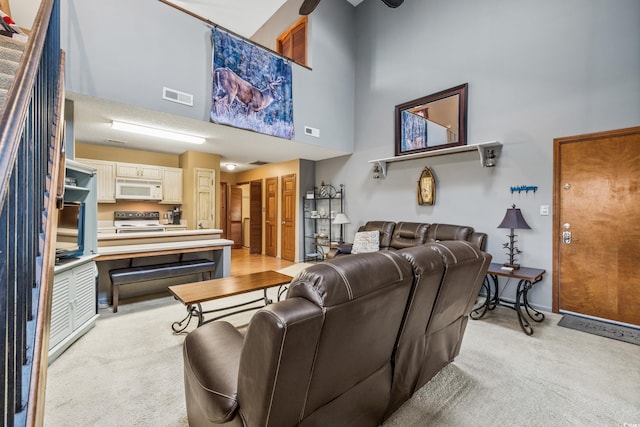 carpeted living room featuring a towering ceiling