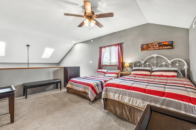 bedroom with vaulted ceiling with skylight, ceiling fan, carpet flooring, and a textured ceiling