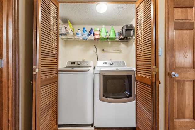 laundry area with independent washer and dryer and a textured ceiling