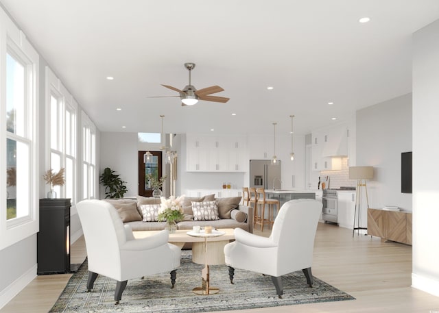 living room featuring ceiling fan, light hardwood / wood-style flooring, and sink