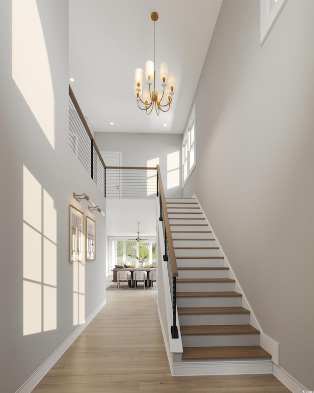 staircase with hardwood / wood-style floors, a high ceiling, and an inviting chandelier