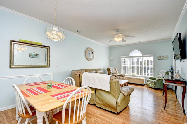 dining area with ceiling fan with notable chandelier, light wood-type flooring, a textured ceiling, and ornamental molding