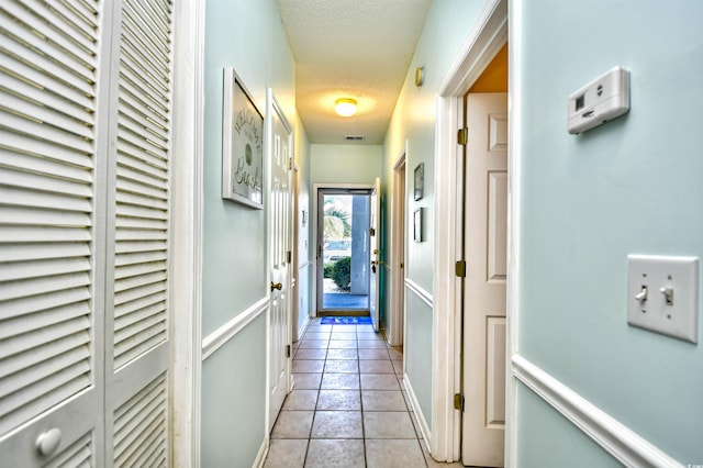 hall featuring a textured ceiling and light tile patterned floors