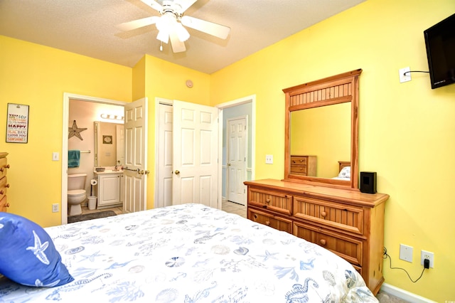 bedroom with a textured ceiling, ensuite bath, and ceiling fan