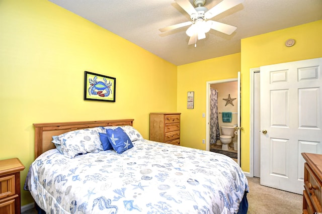 carpeted bedroom featuring ceiling fan, a textured ceiling, and ensuite bath