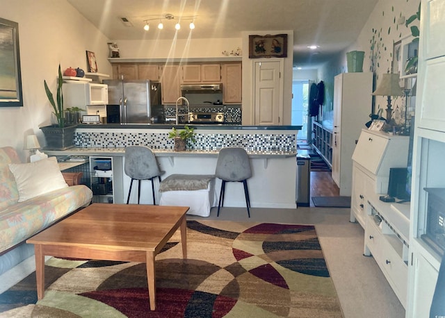 kitchen with decorative backsplash, stainless steel fridge, and sink