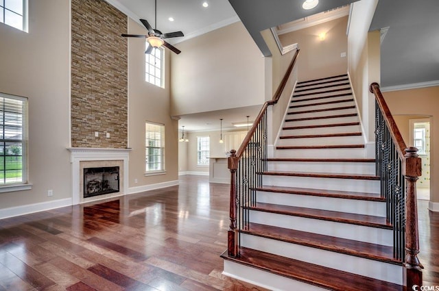 staircase featuring a fireplace, a high ceiling, hardwood / wood-style floors, and a wealth of natural light