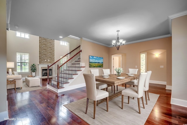 spare room with wood-type flooring, a notable chandelier, a fireplace, and crown molding