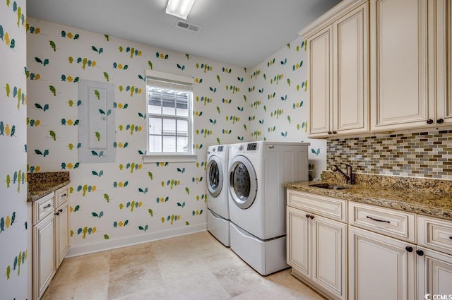 clothes washing area featuring washer and dryer, sink, and cabinets