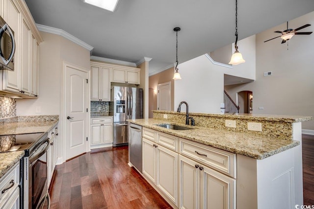 kitchen featuring dark hardwood / wood-style floors, sink, cream cabinets, hanging light fixtures, and appliances with stainless steel finishes