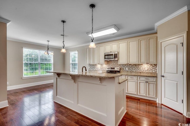 kitchen with a center island with sink, cream cabinets, appliances with stainless steel finishes, and a wealth of natural light